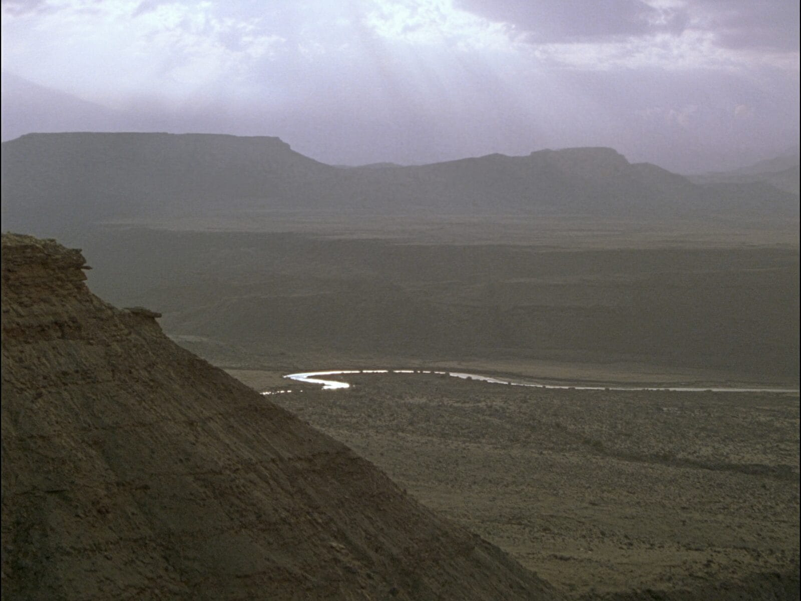 A wide Western basin seen from a high bench under breaking light at last light.